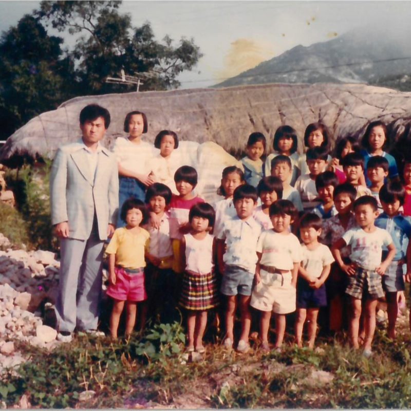 초가지붕 앞에 선 김영수 목사와 마을 아이들 서른여 명.