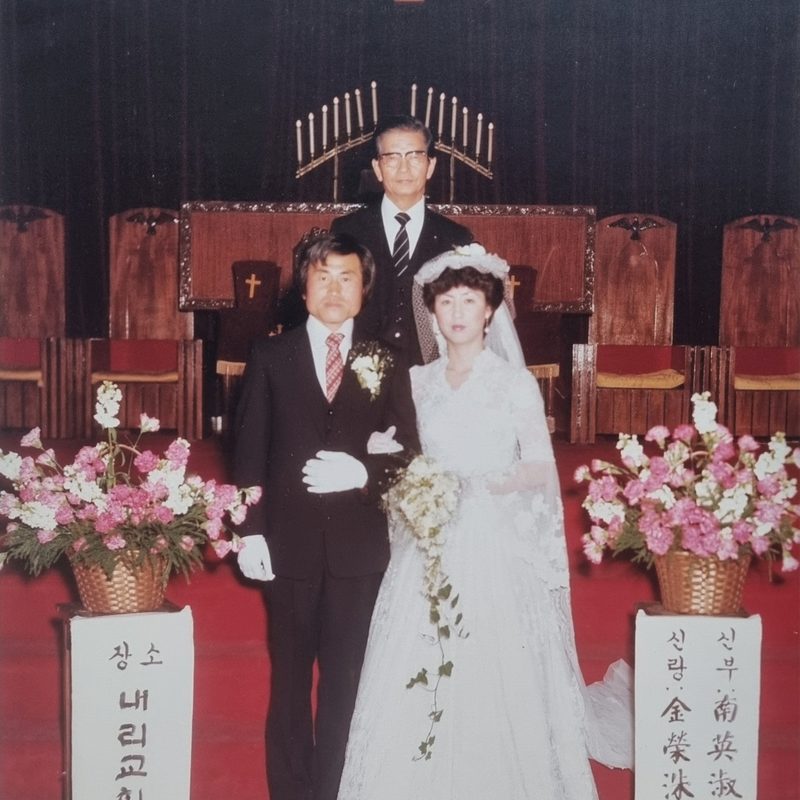 예식장 단상에 선 신랑 김영수와 신부 남영숙, 뒤에 주례 목사.